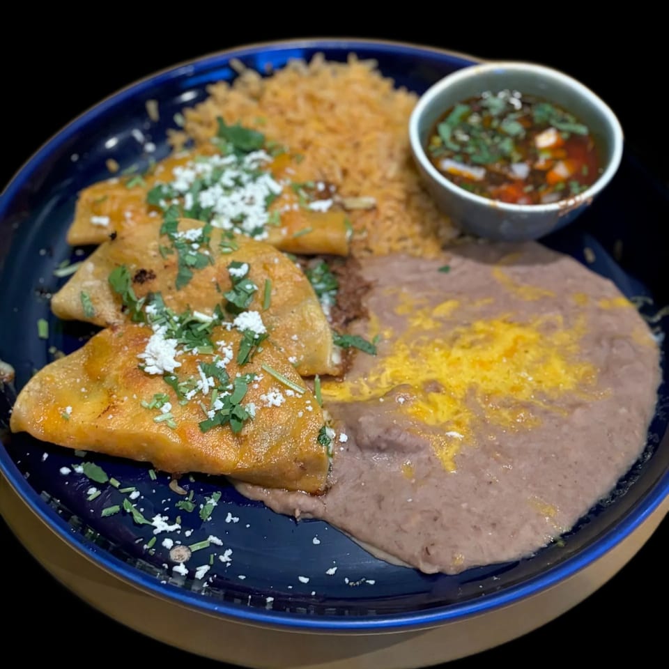 Three golden-brown El Tenampa Mexican Grill & Cantina tacos with rice, refried beans, and a side of salsa.
